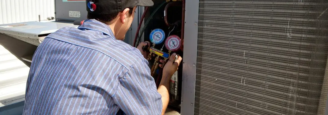 HVAC technician servicing a condenser unit in Jenks