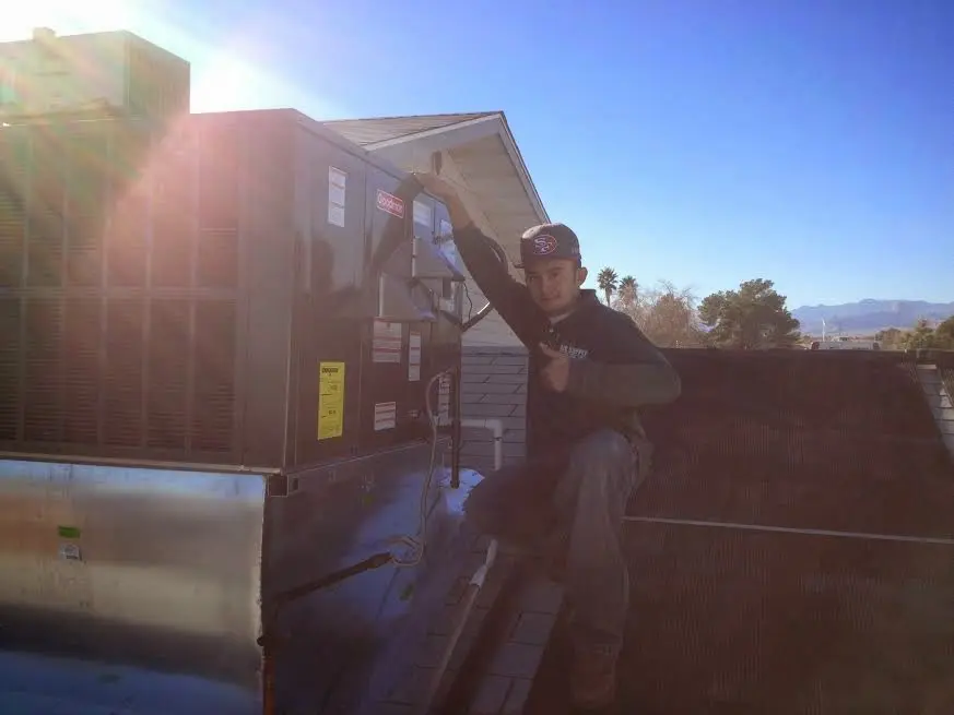 HVAC technician performing Air Duct Cleaning on a rooftop unit in Jenks